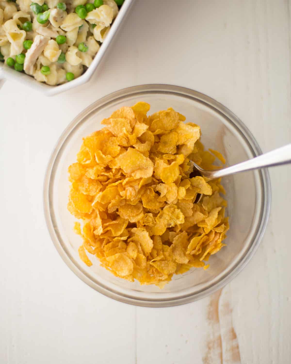 overhead image of a spoon and cornflakes in a glass bowl