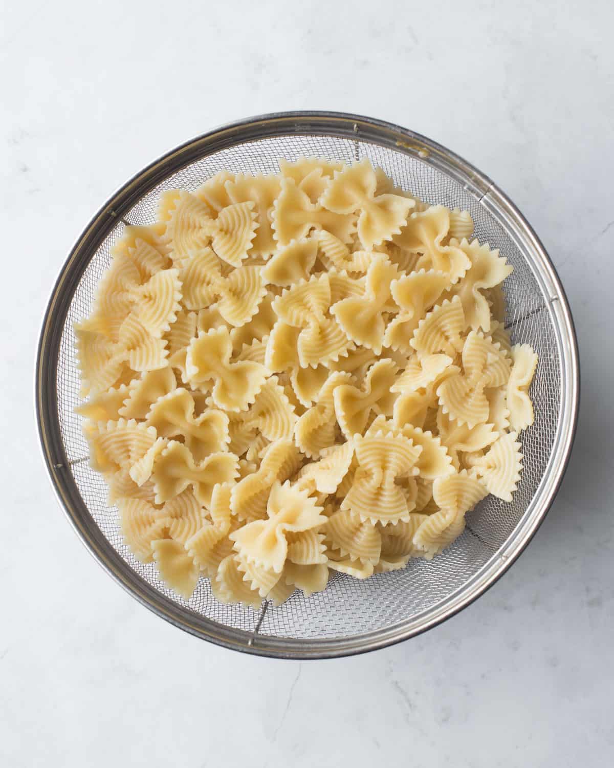 overhead image of cooked bowtie noodles in a colander