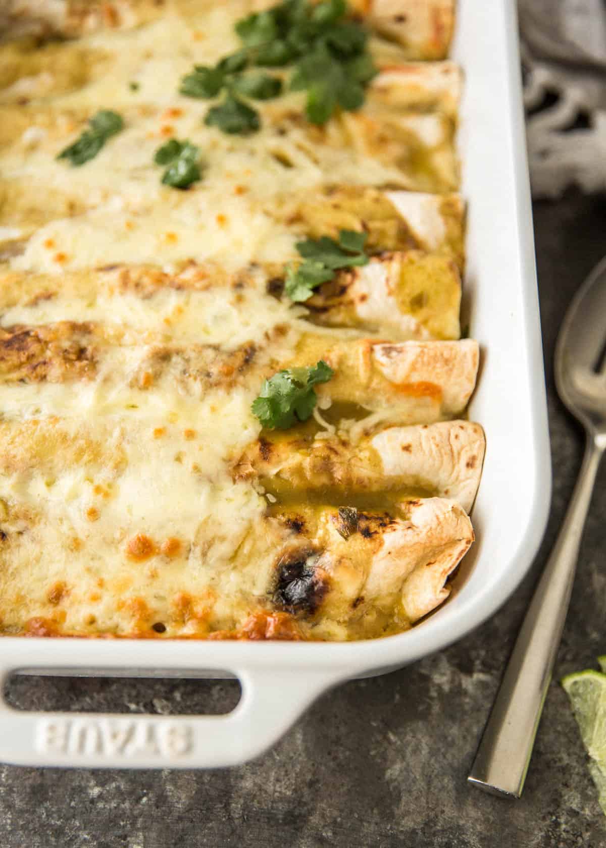 a white dish of enchiladas on a table