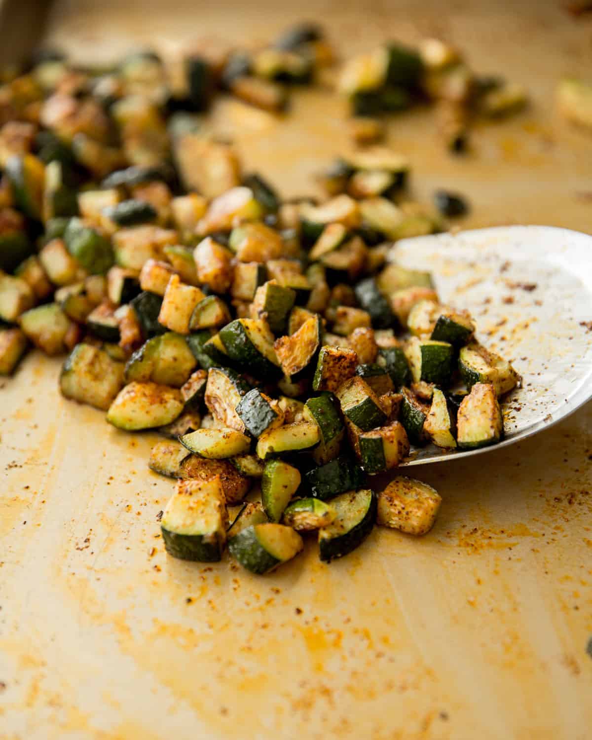 cubed, cooked zucchini spilling off a white plate