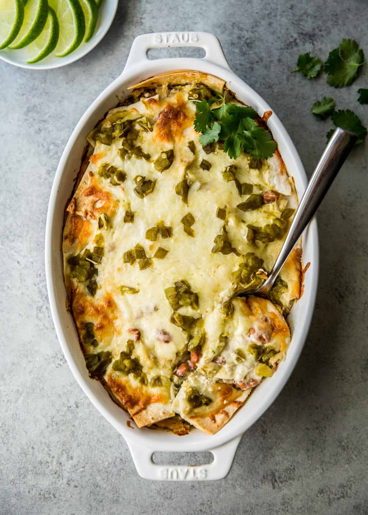 enchilada casserole in a white oval baking dish