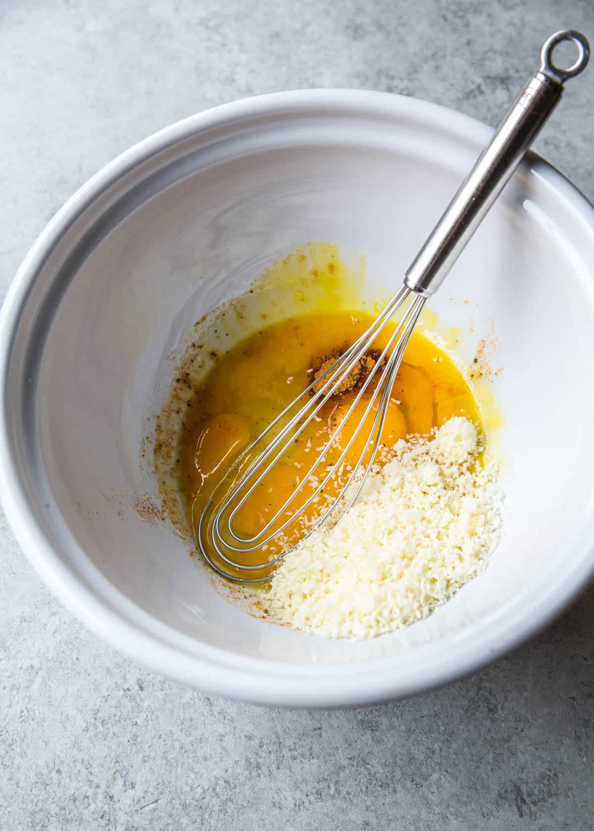 overhead image of stirring eggs in a white bowl with a whisk