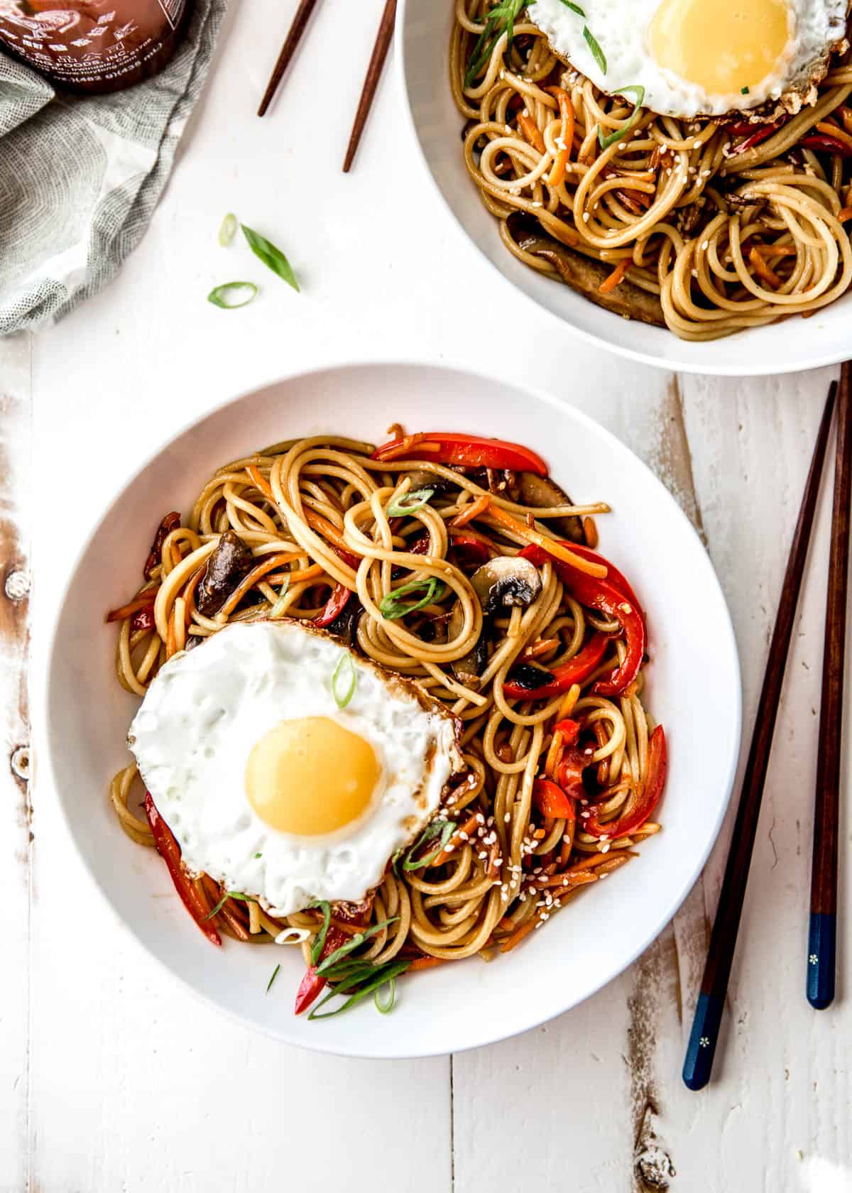 sesame noodles with a fried egg in a white bowl