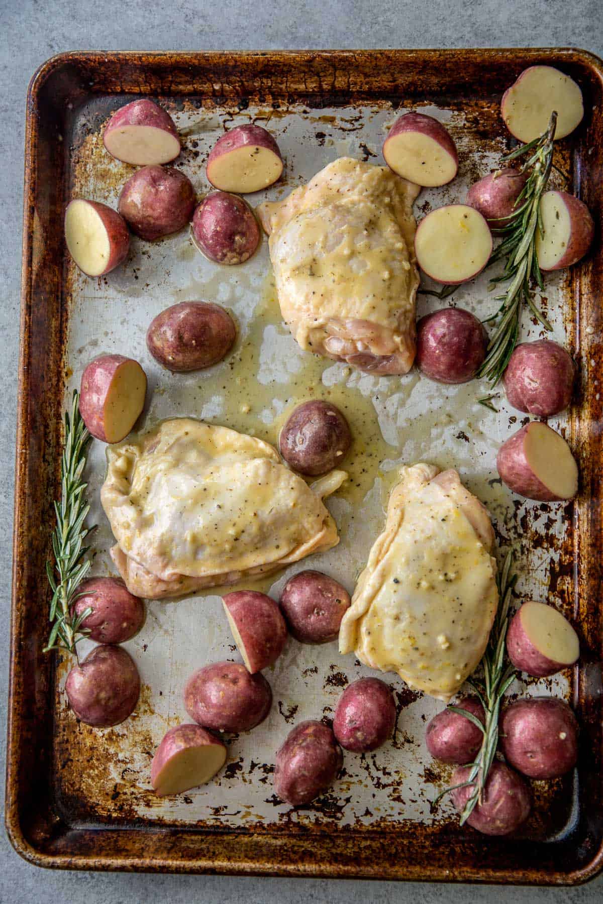 overhead image of chicken thighs and potatoes on a sheet pan