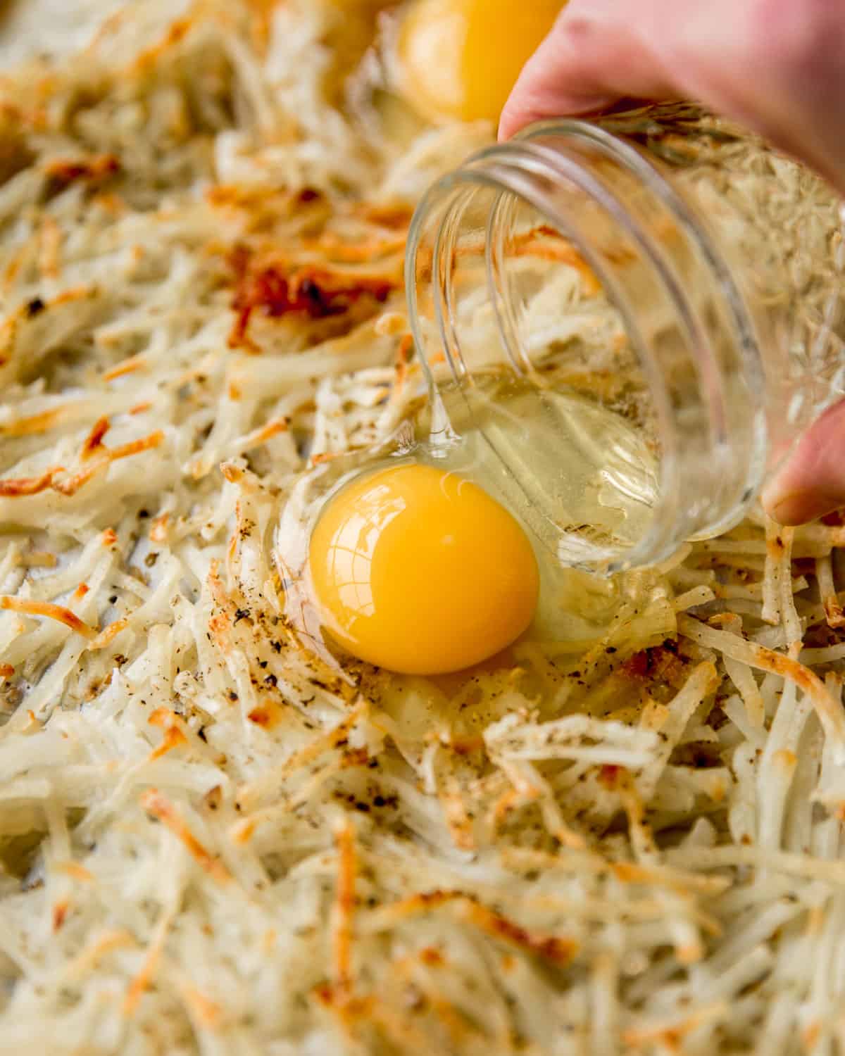 adding egg to potatoes on a sheet pan