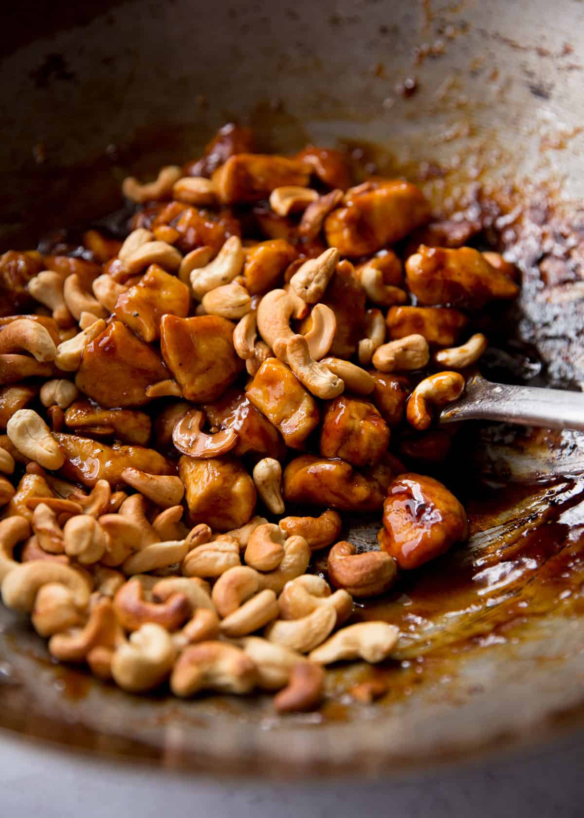 stirring chicken and sauce in a wok