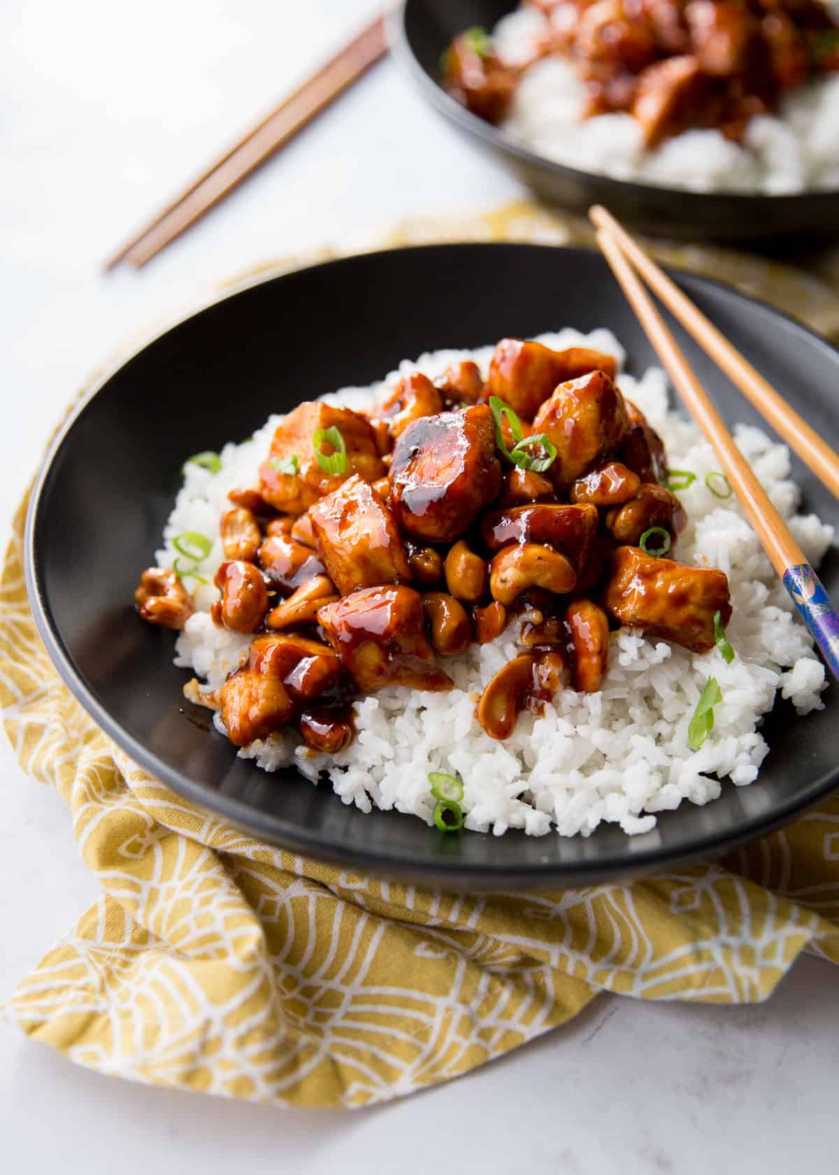 chicken and rice in a black bowl with chopsticks