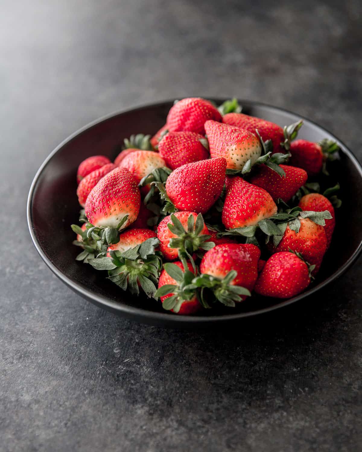 fresh strawberries in a black bowl