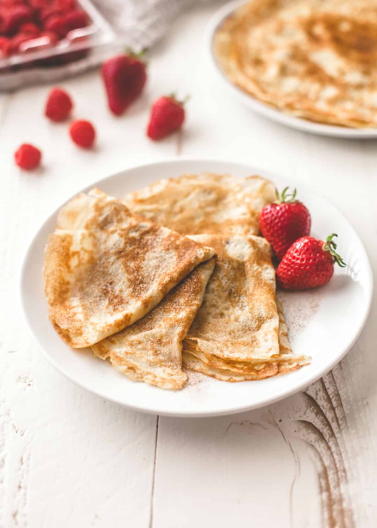 overhead image of crepes and berries on a white plate