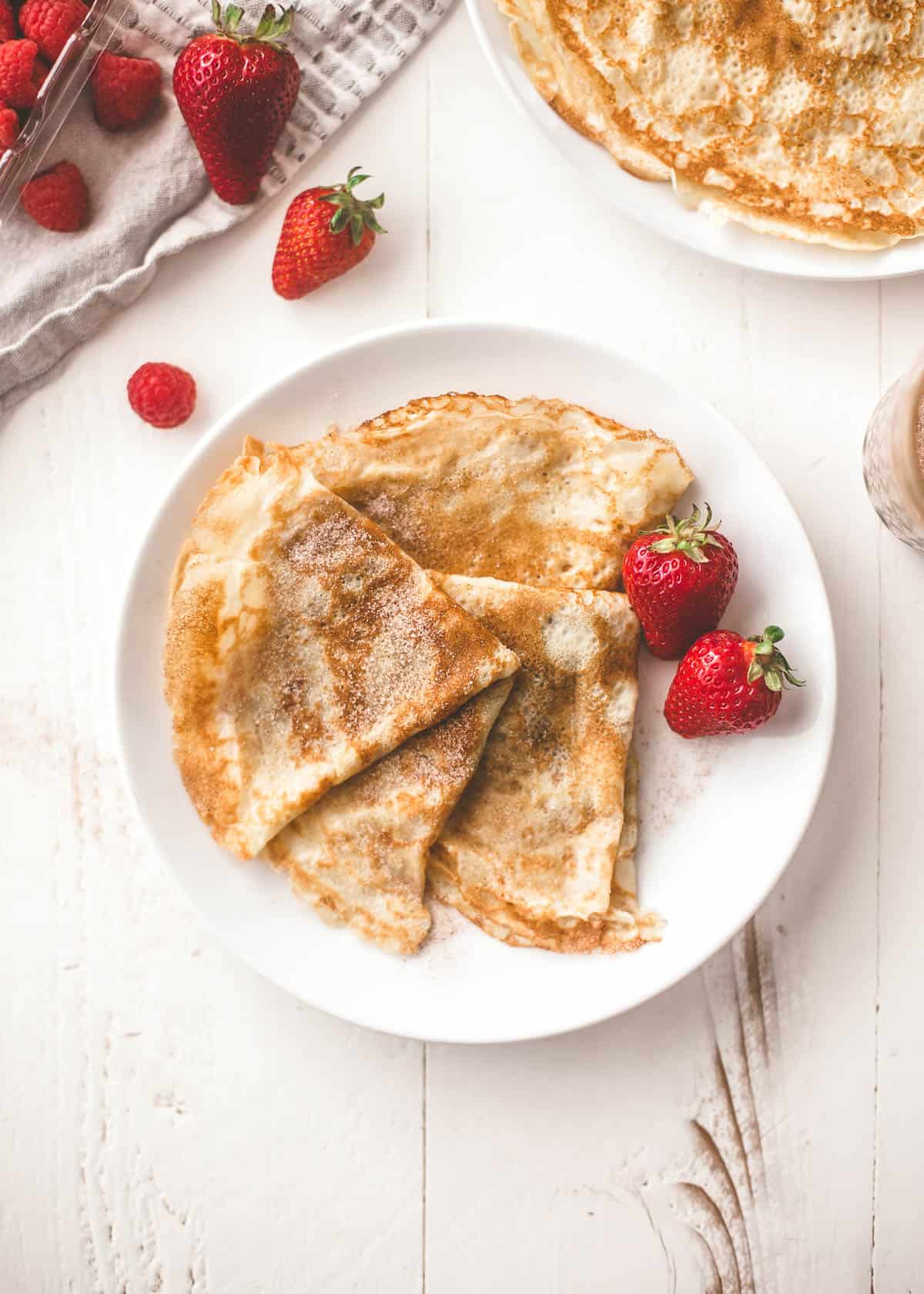 overhead image of crepes and berries on a white plate