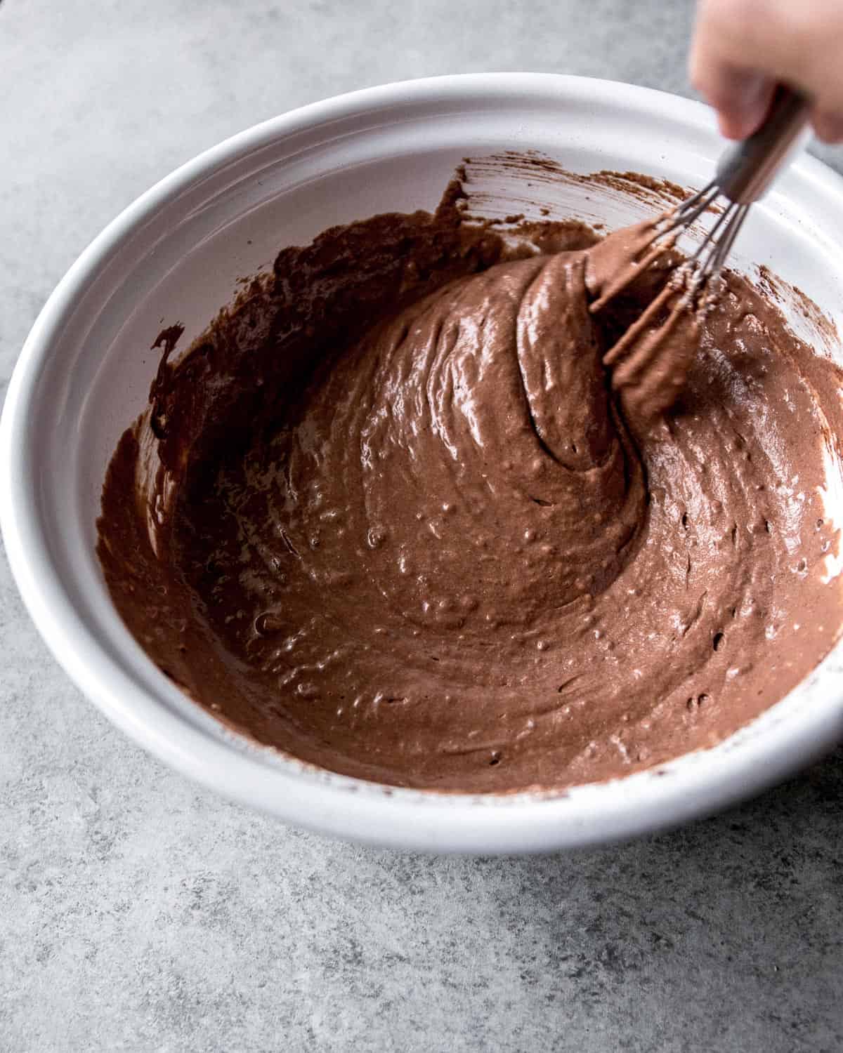 stirring pancake batter in a white bowl