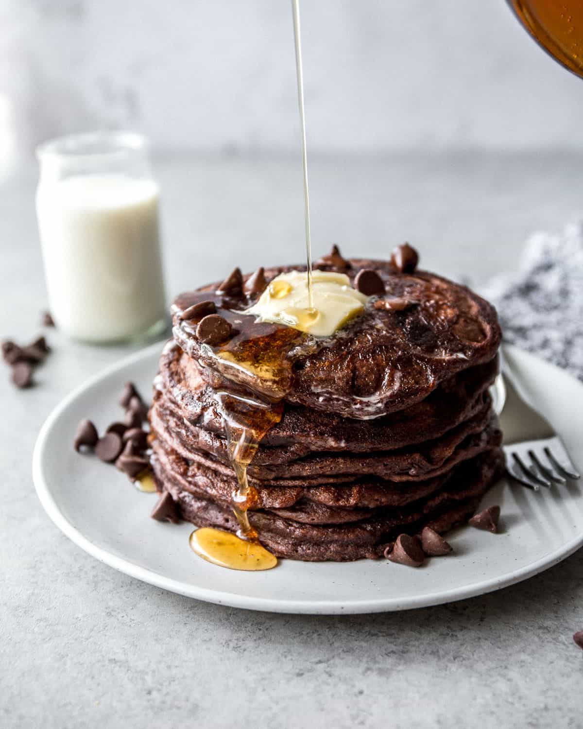 a stack of chocolate pancakes on a white plate