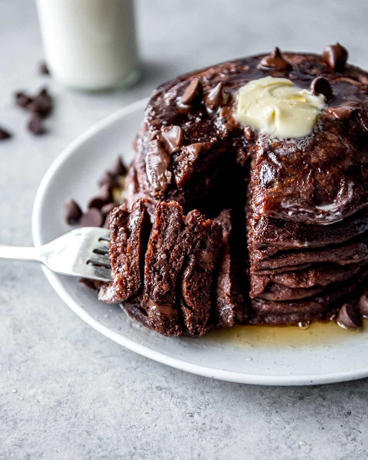 a fork and a stack of pancakes on a white plate