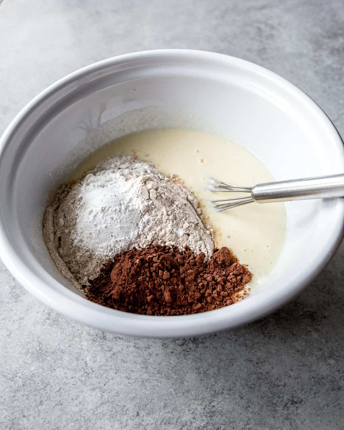 overhead image of ingredients for pancakes in a white mixing bowl