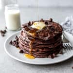 a stack of pancakes with butter and syrup on a white plate