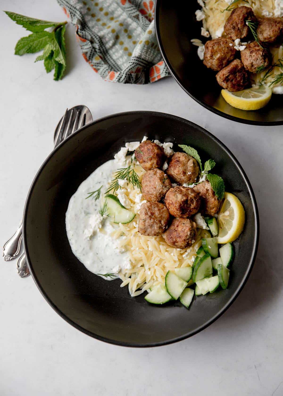 overhead image of meatballs and orzo in a black bowl