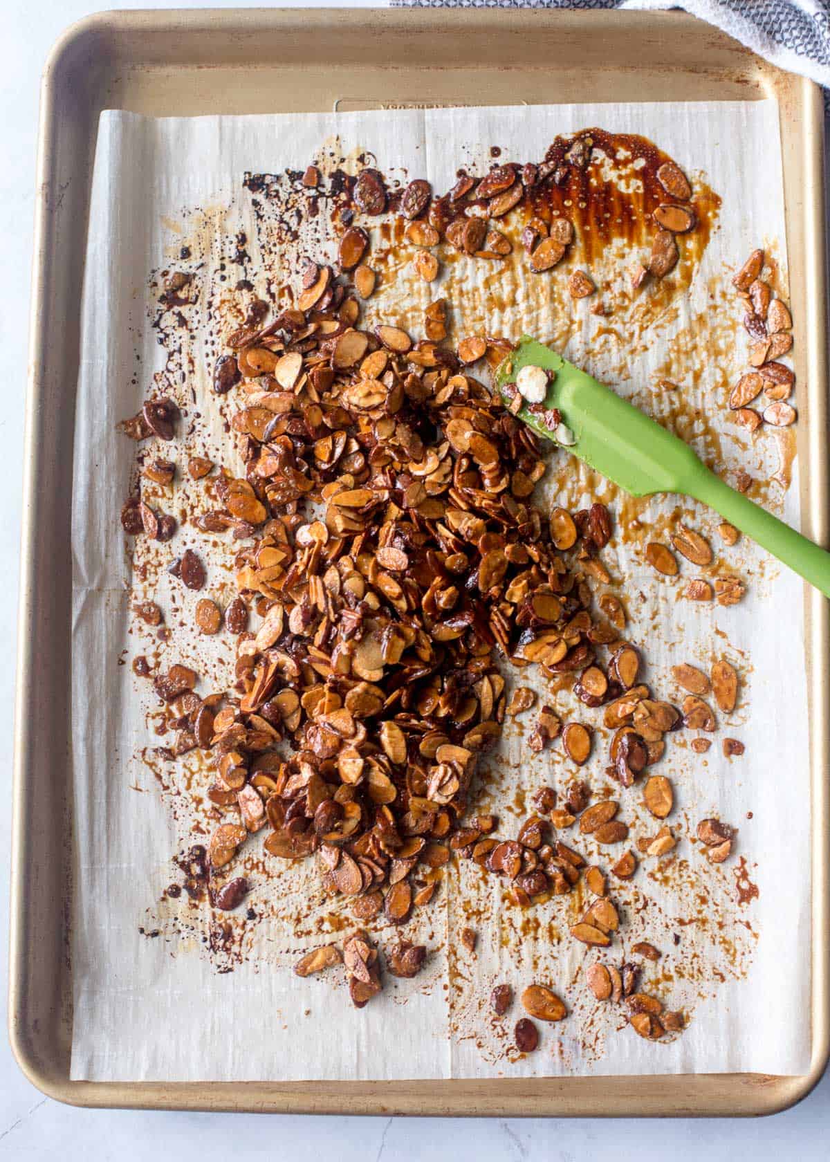 spreading candied almonds on a parchment lined sheet pan