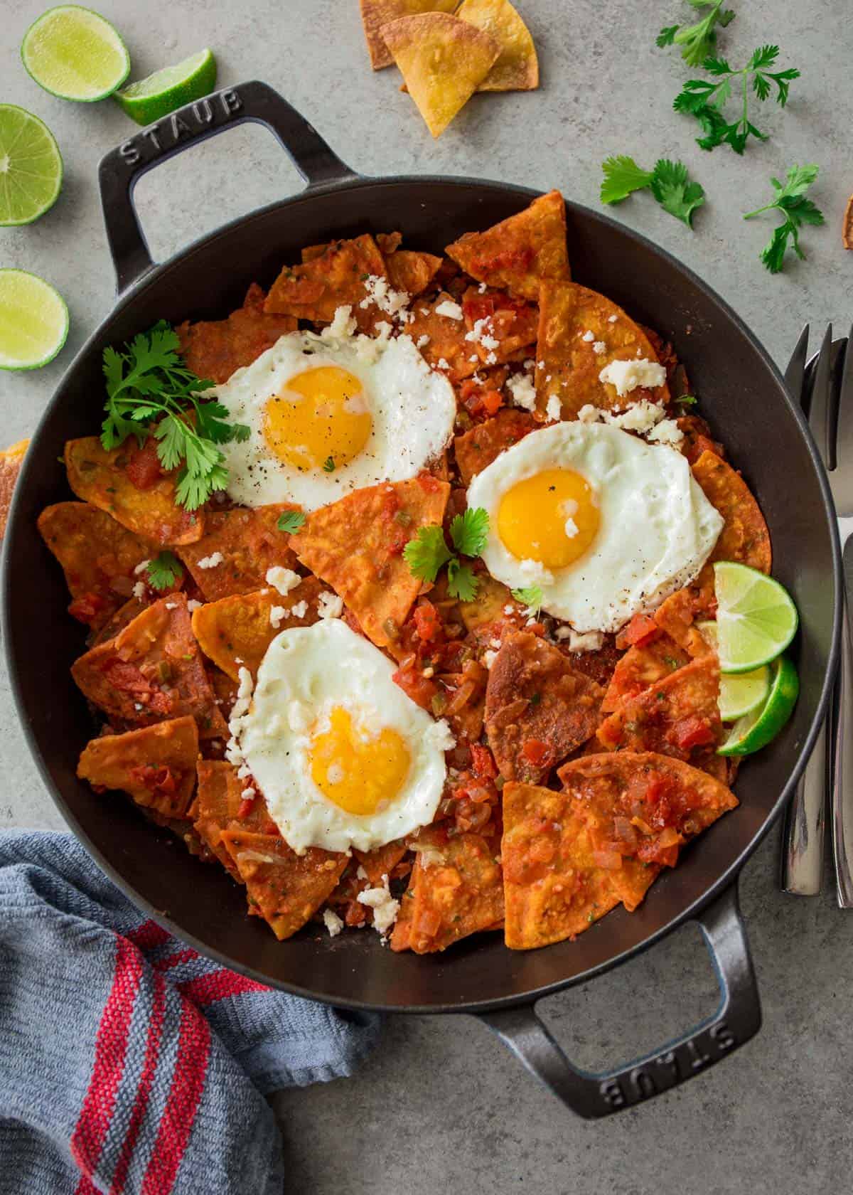 chips, tomatoes and fried eggs in a cast iron skillet