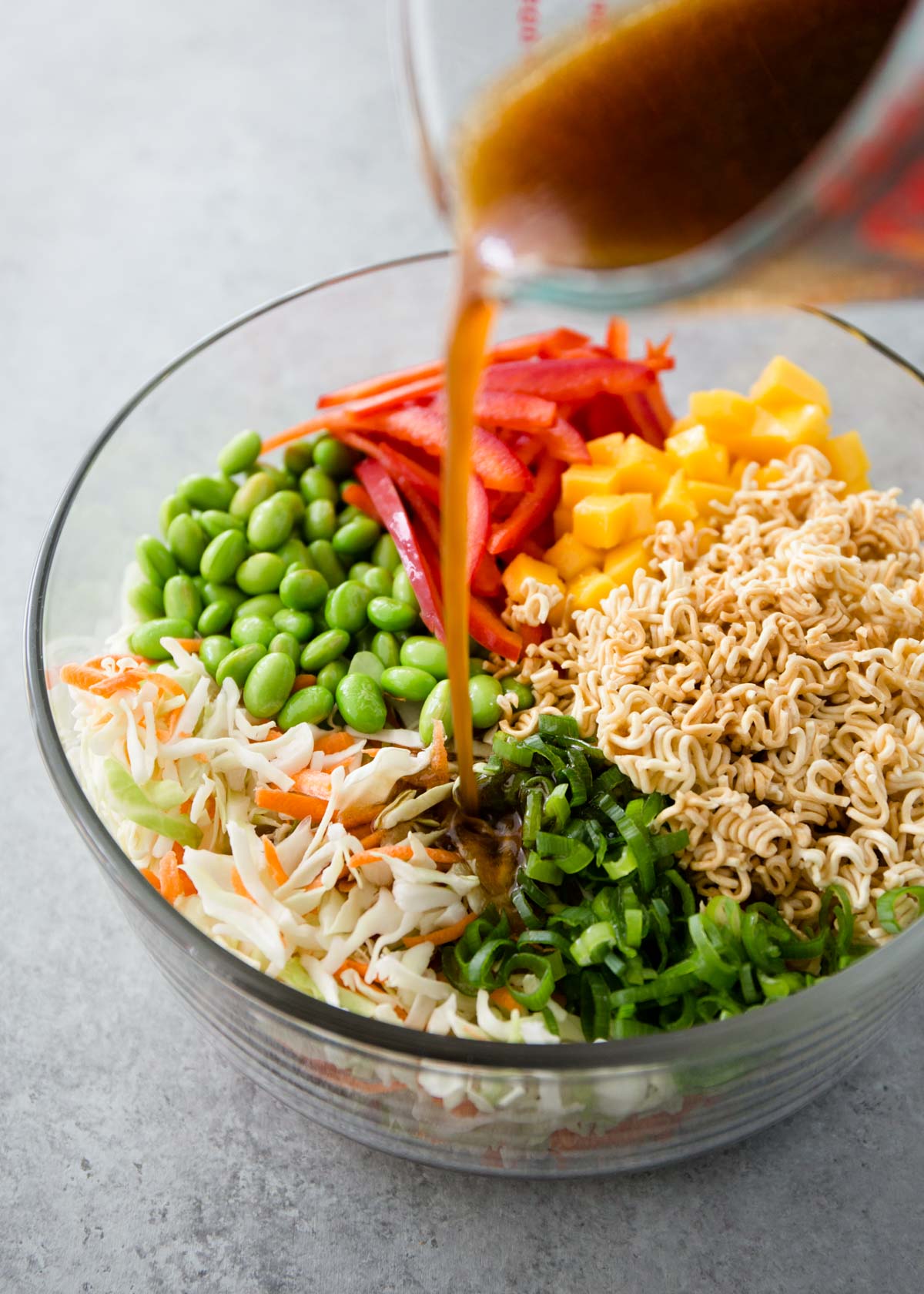 dressing being poured over crunchy ramen noodle salad