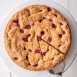 square image of overhead shot of raspberry almond cake on a white cake stand
