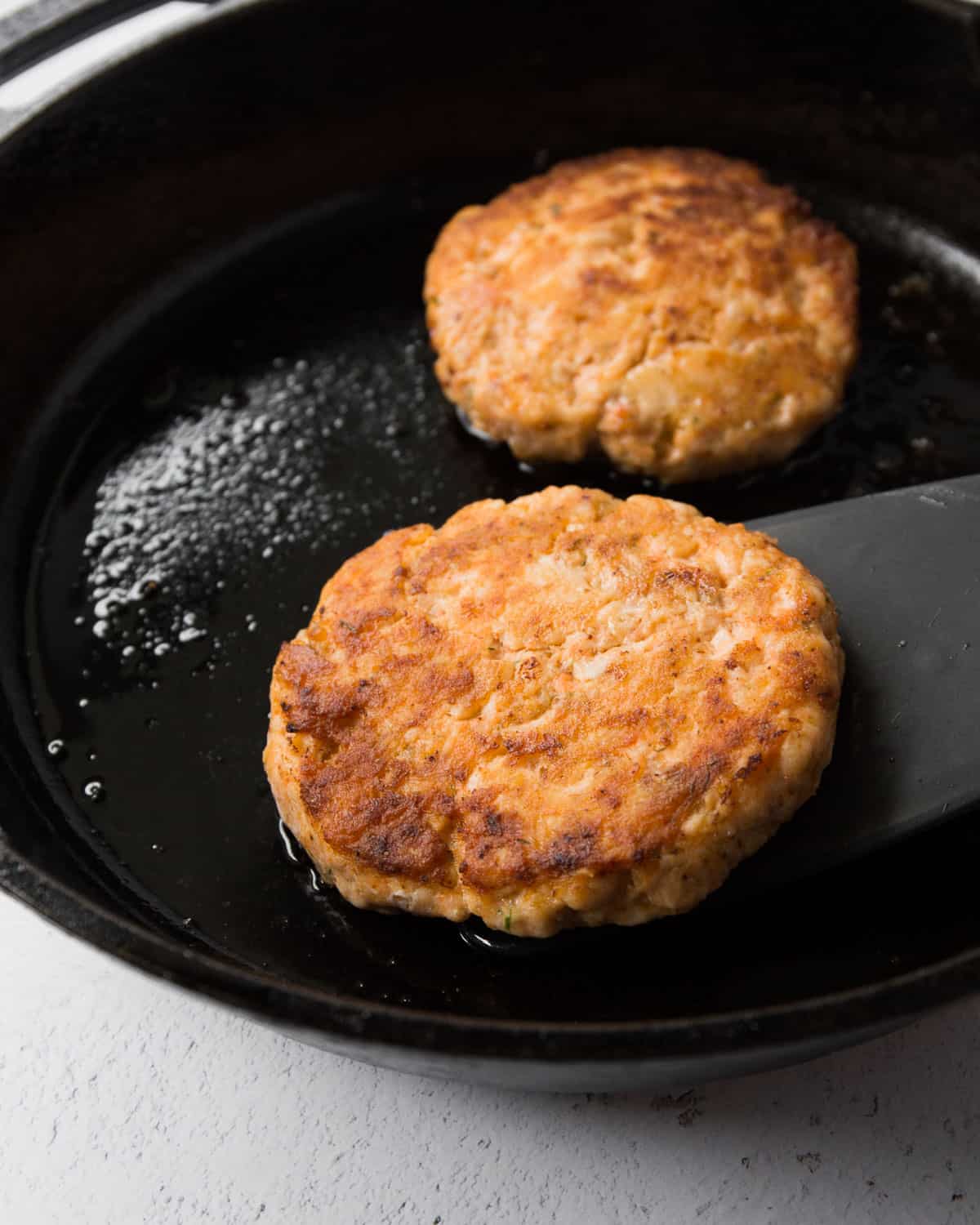 cooking salmon burgers in a cast iron skillet