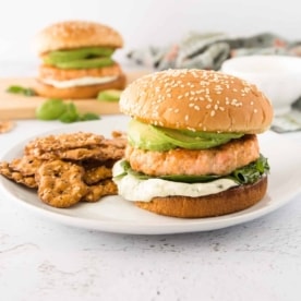 a salmon burger on a bun on a white plate