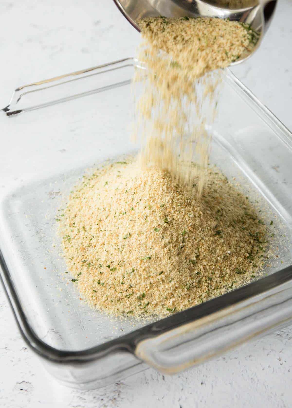 adding breadcrumbs to a square baking dish