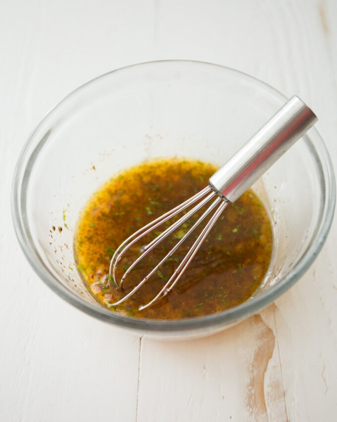 stirring vinaigrette in a clear glass bowl