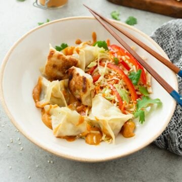 potstickers in a white bowl with chopsticks