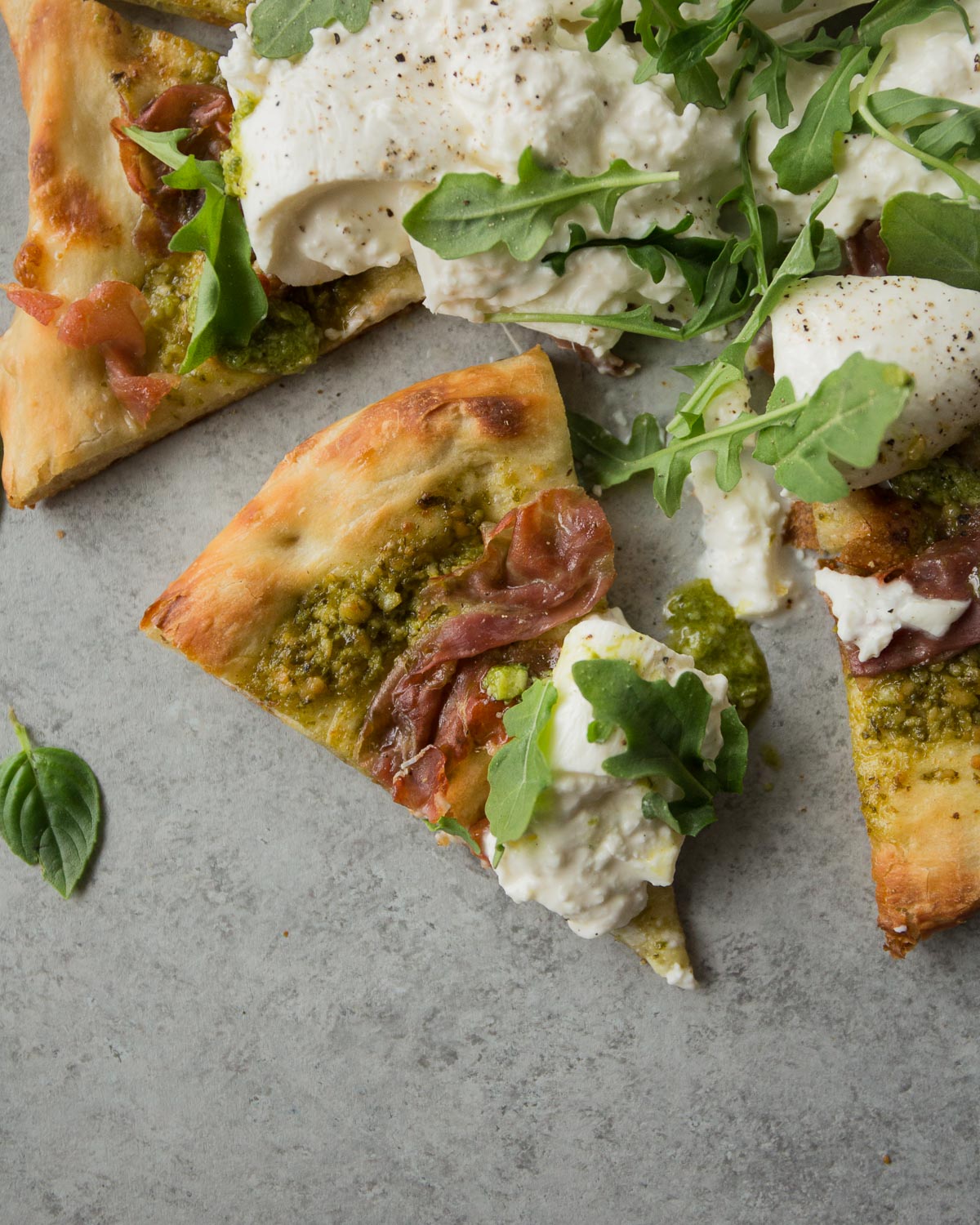 overhead image of a slice of homemade pesto pizza on a countertop