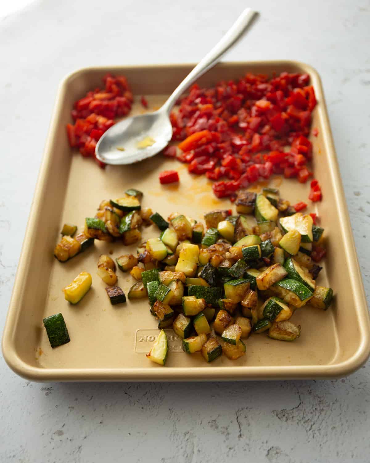 red peppers and zucchini pieces on a sheet pan