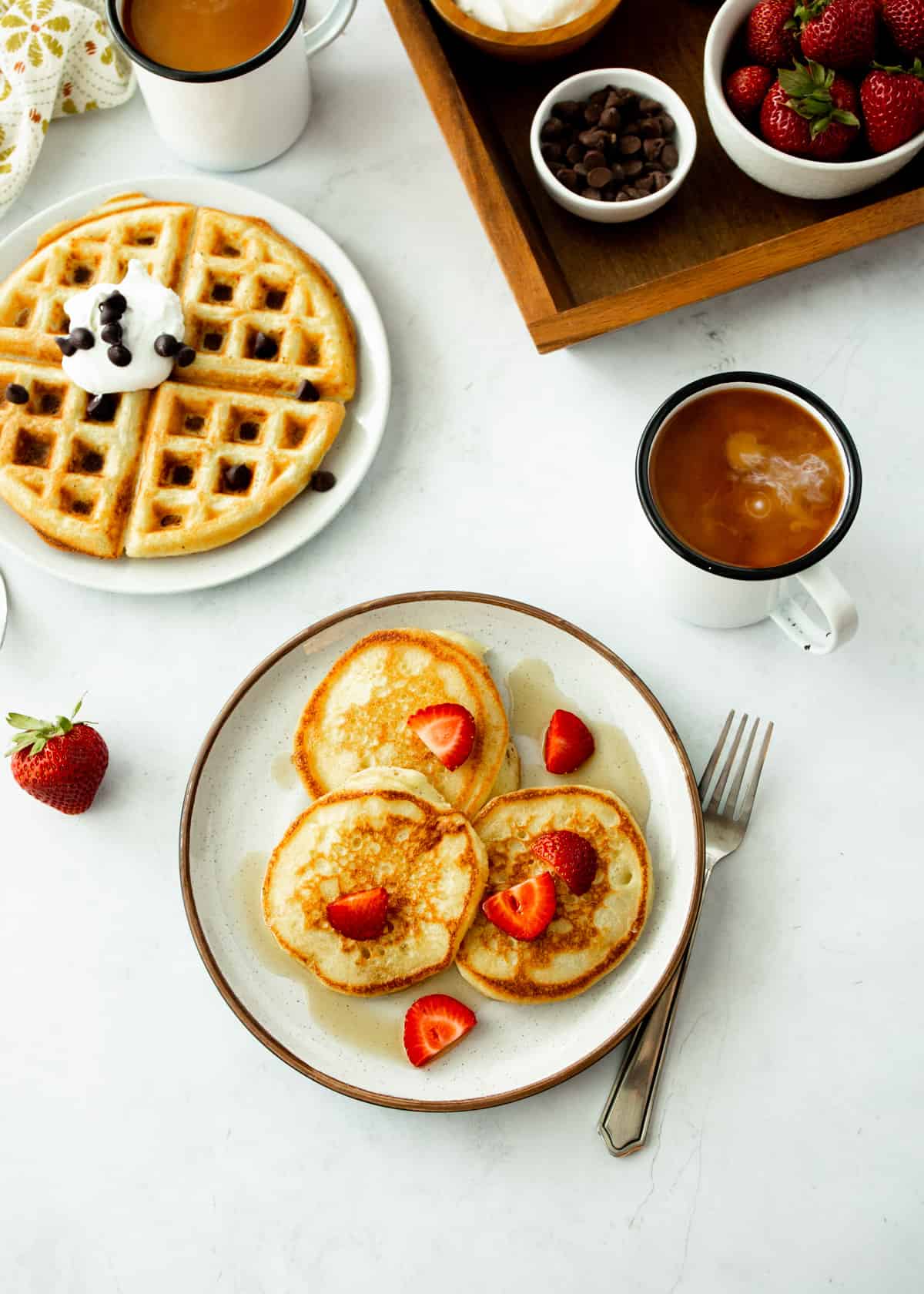 overhead image of pancakes and waffles on white plates