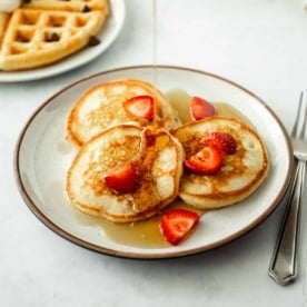 pouring syrup over pancakes with strawberries_square