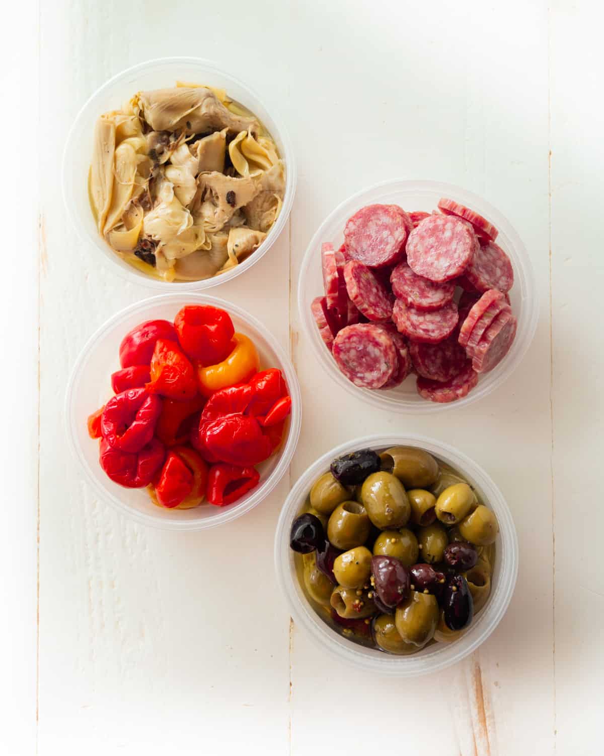 peppers, tortellini, sausage and olives in white bowls