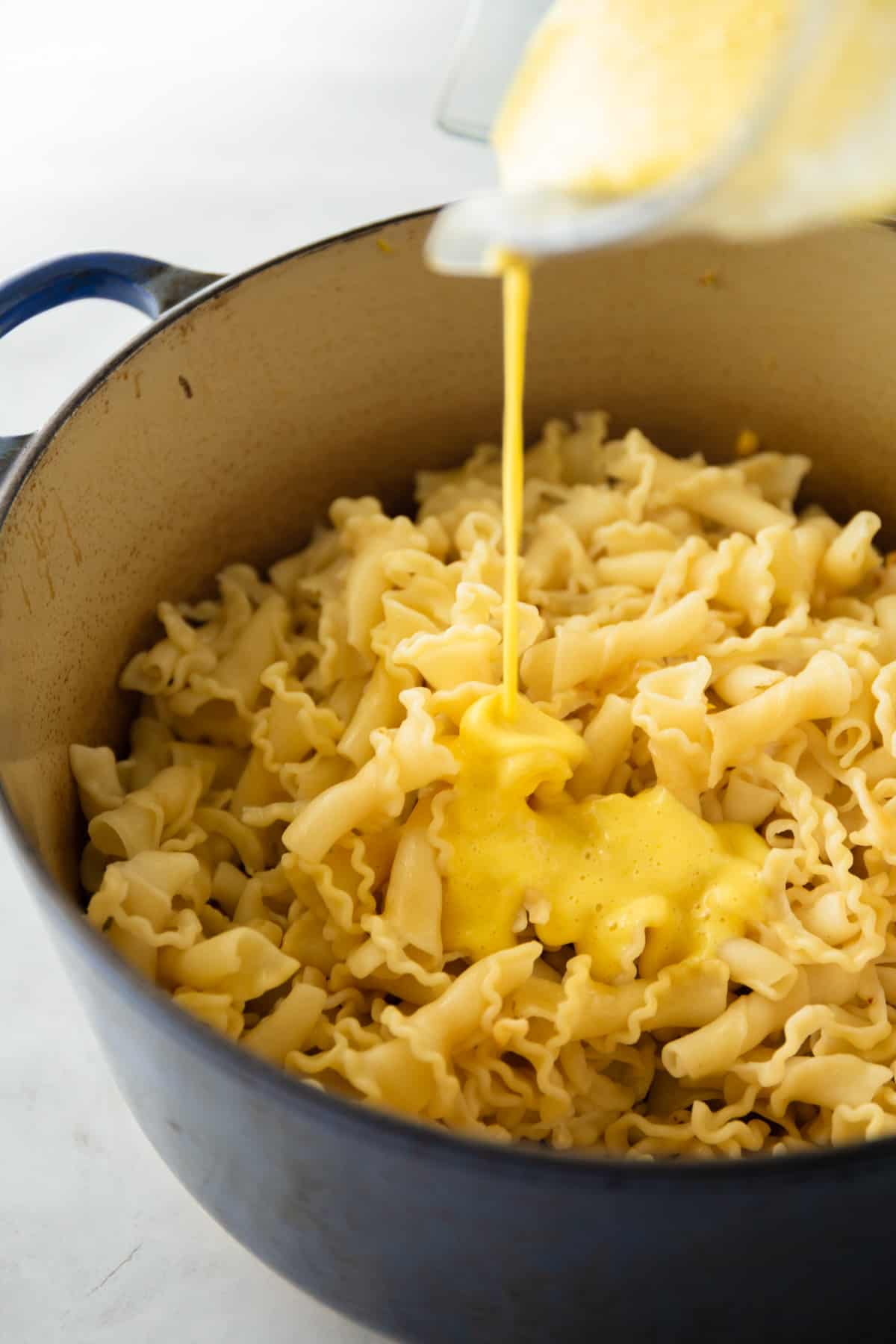 adding sauce to pasta in a dutch oven