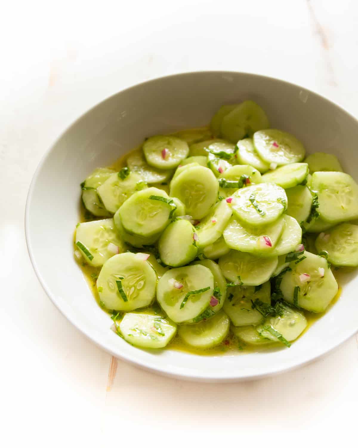 overhead image of marinated cucumbers in a white bowl