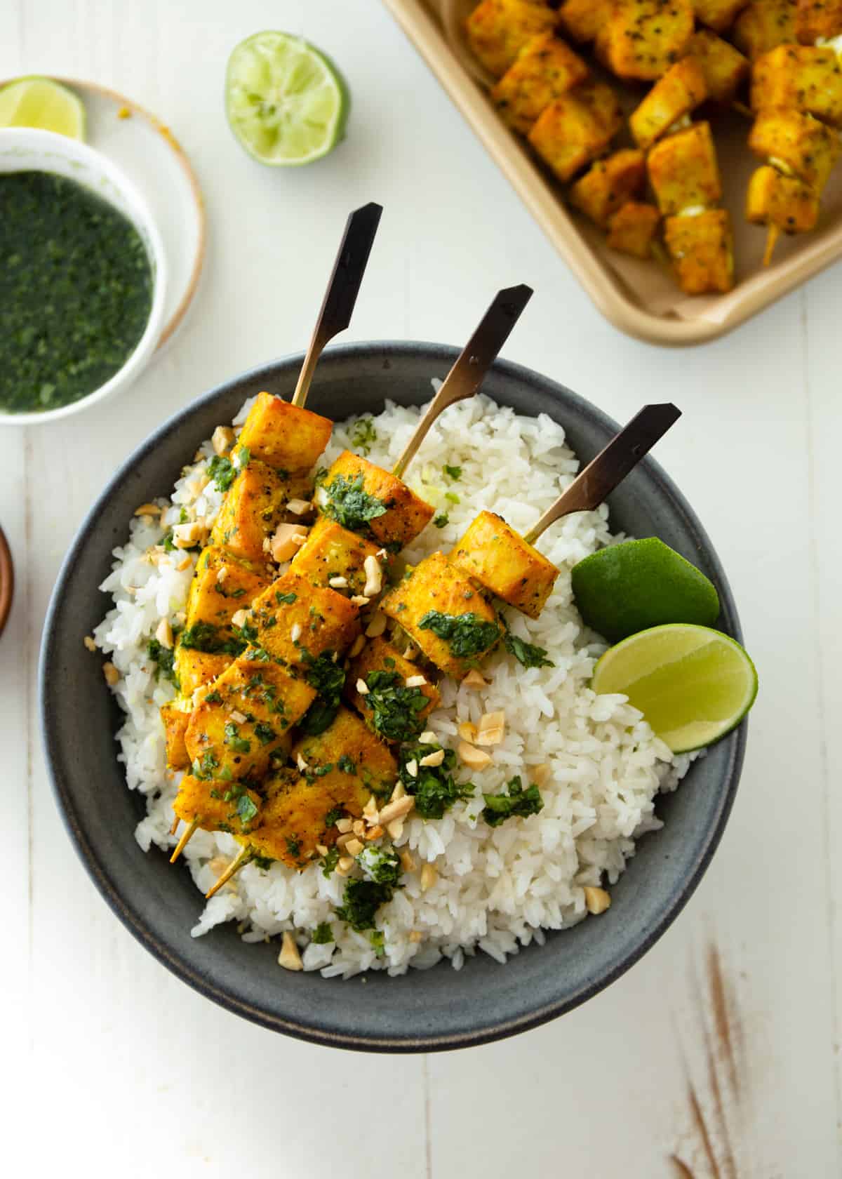 fish skewers over rice in a black bowl