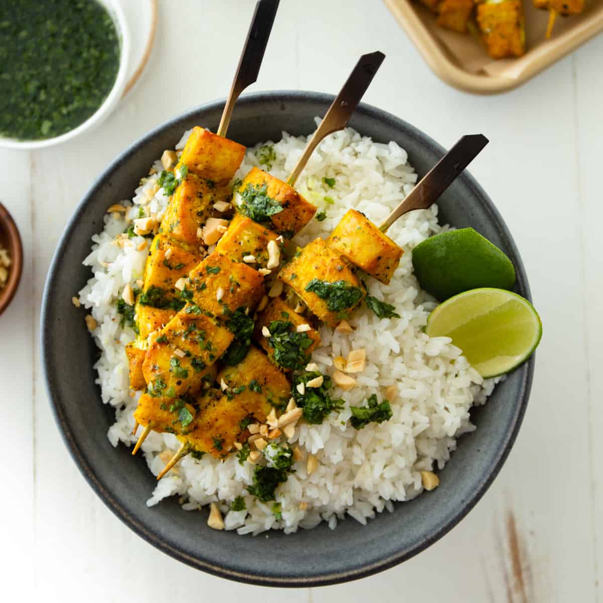 fish skewers on a bed of rice in a black bowl