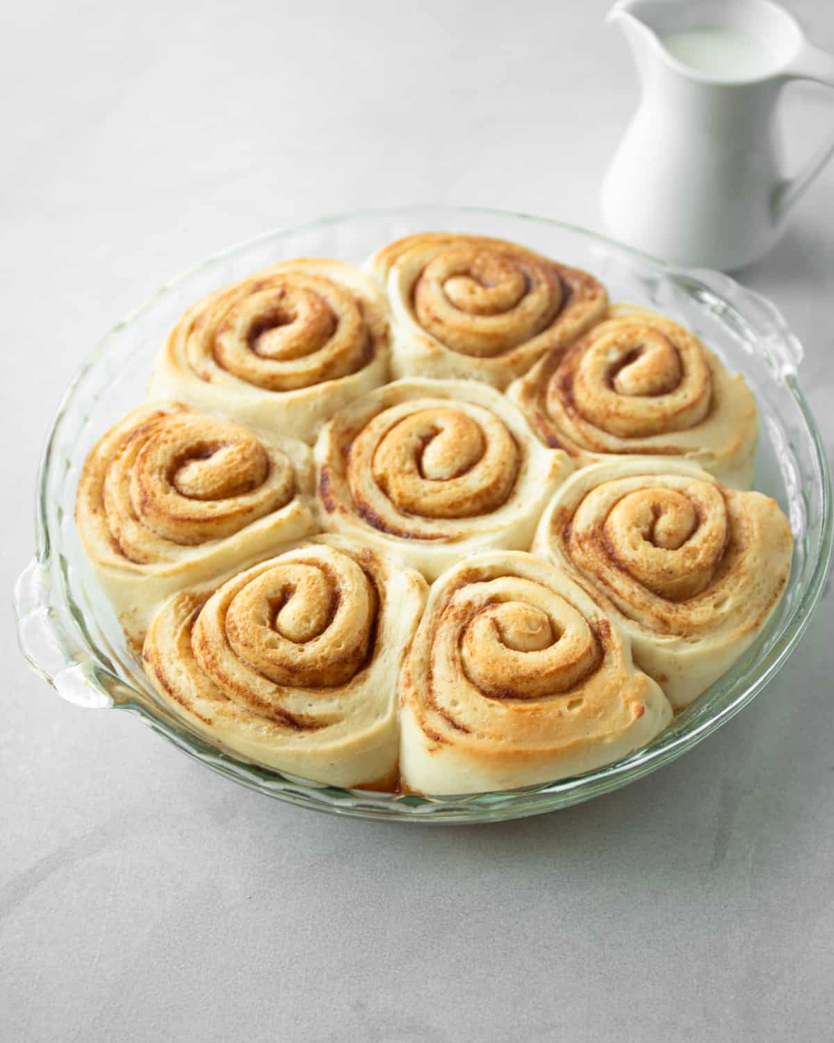 risen cinnamon rolls in a clear baking dish