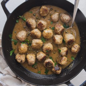 square image of chicken piccata meatballs in a sauce with a spoon