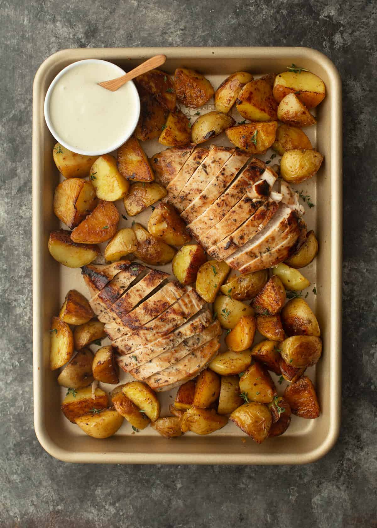 overhead image of potatoes and herb marinated chicken on a sheet pan