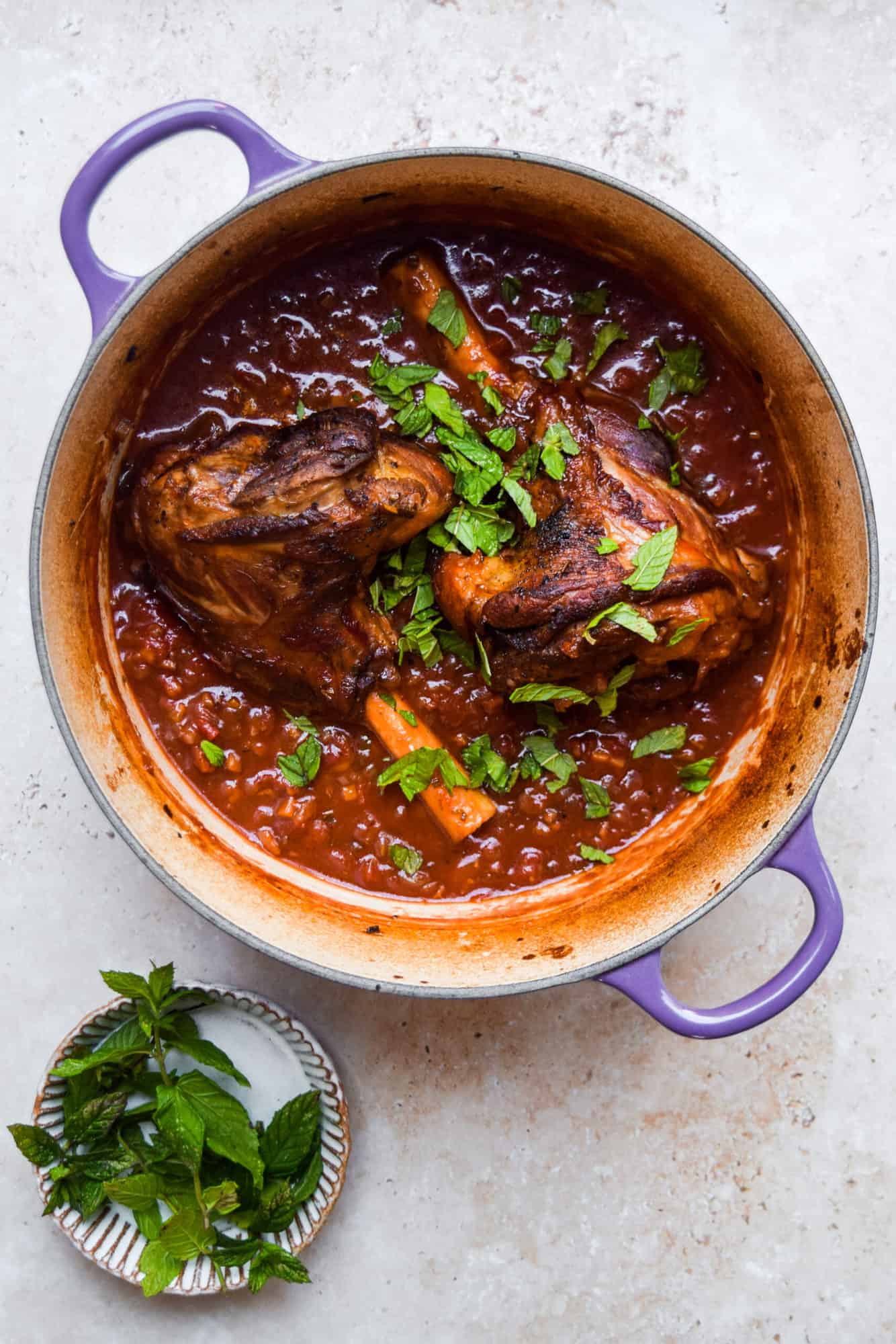 tomato braised lamb shanks in a blue dutch oven