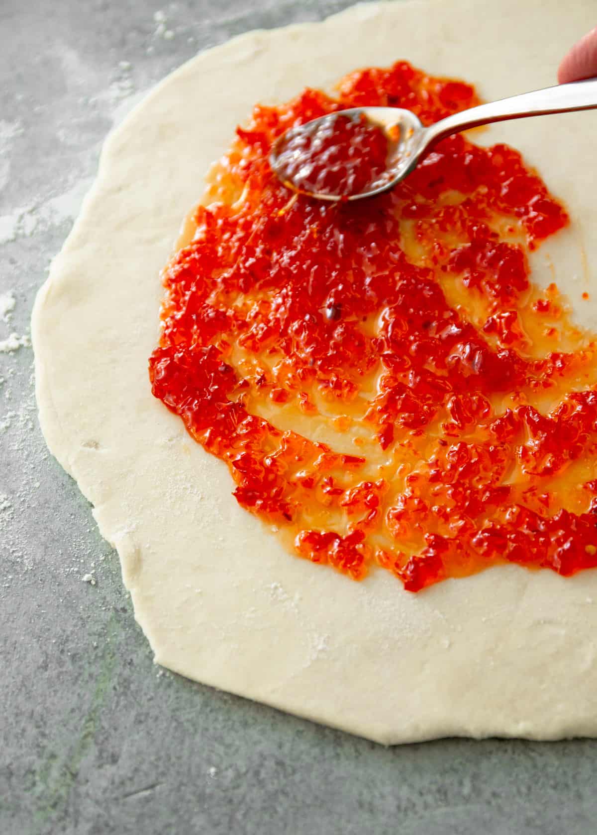 spreading red pepper jelly on dough