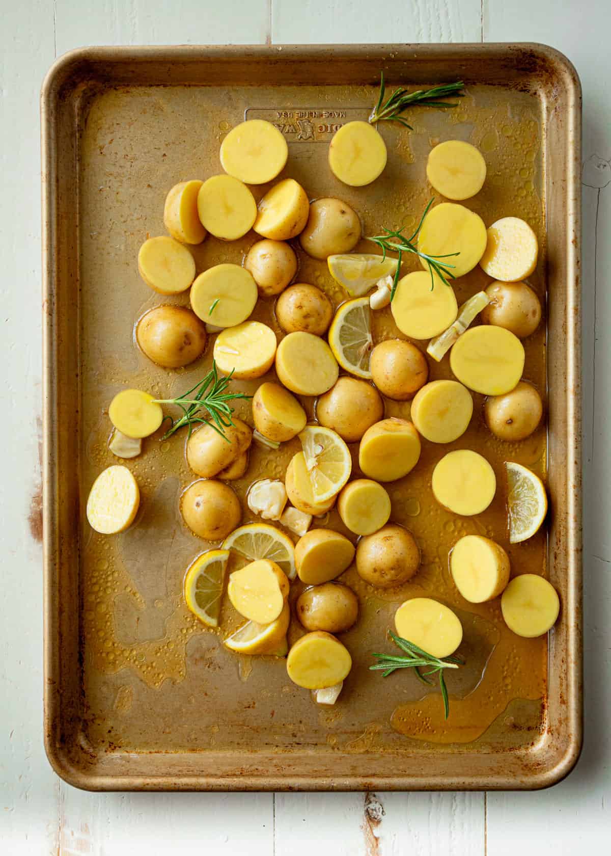 overhead image of uncooked potatoes and lemon slices on a sheet pan