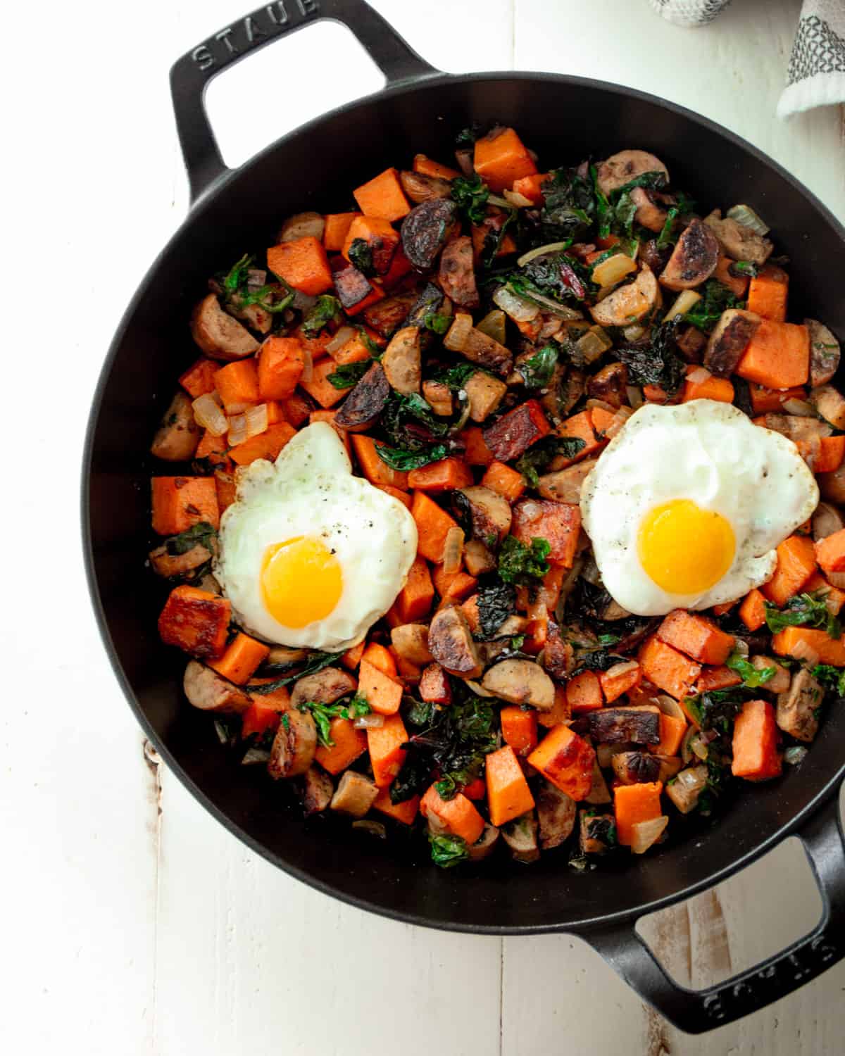 overhead image of hash in a cast iron skillet topped with fried eggs