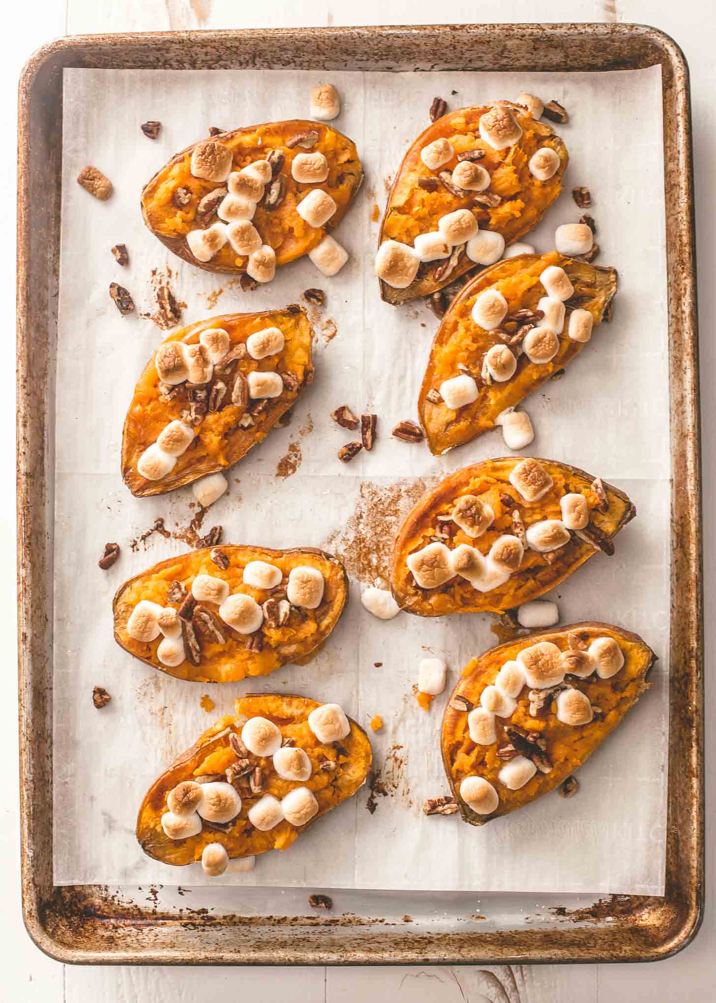 twice baked sweet potatoes on a parchment lined sheet pan