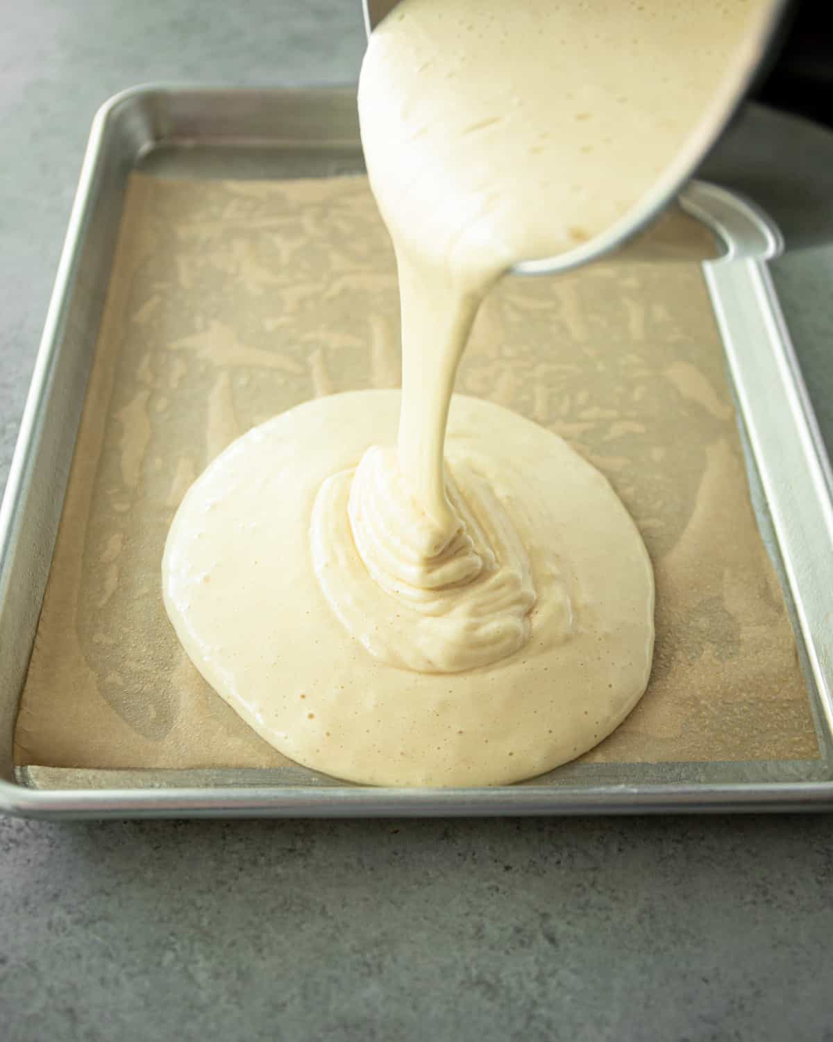 adding cake batter to a sheet pan