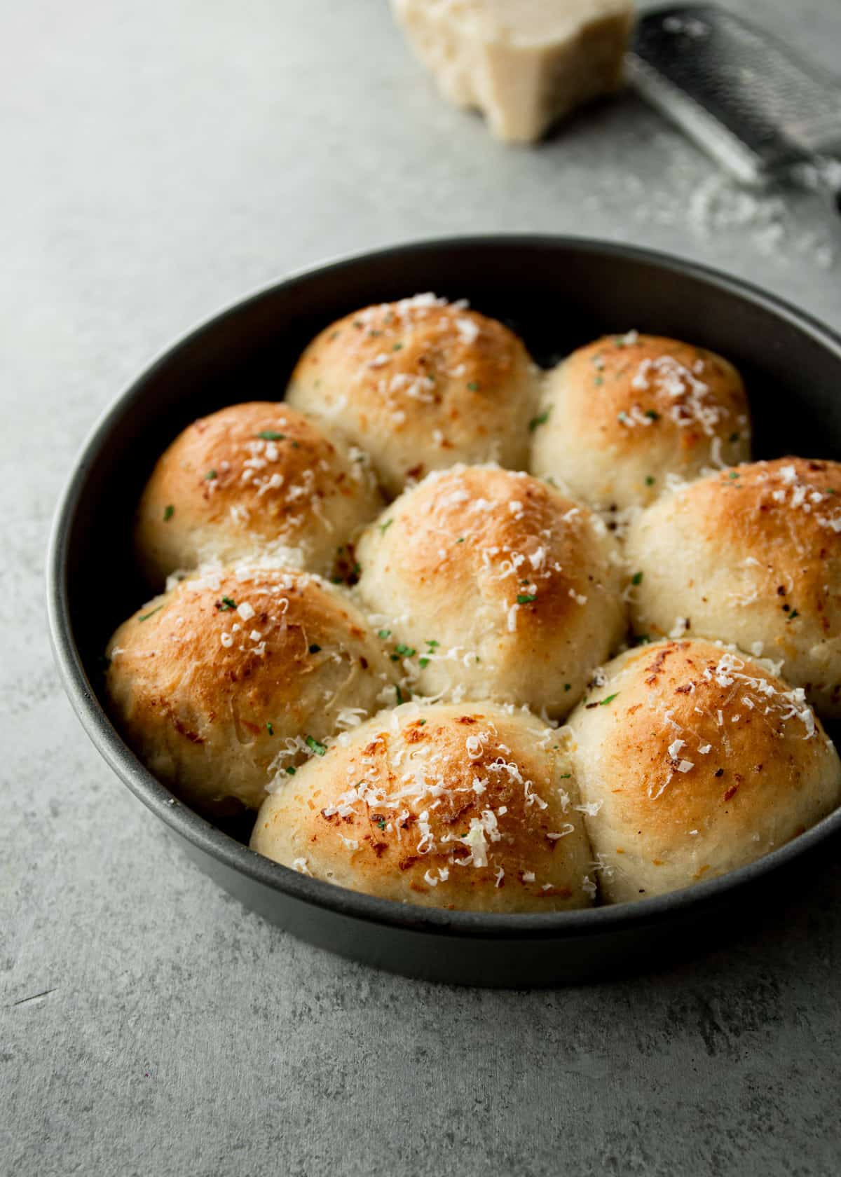 garlic and parmesan dinner rolls in a round cake pan