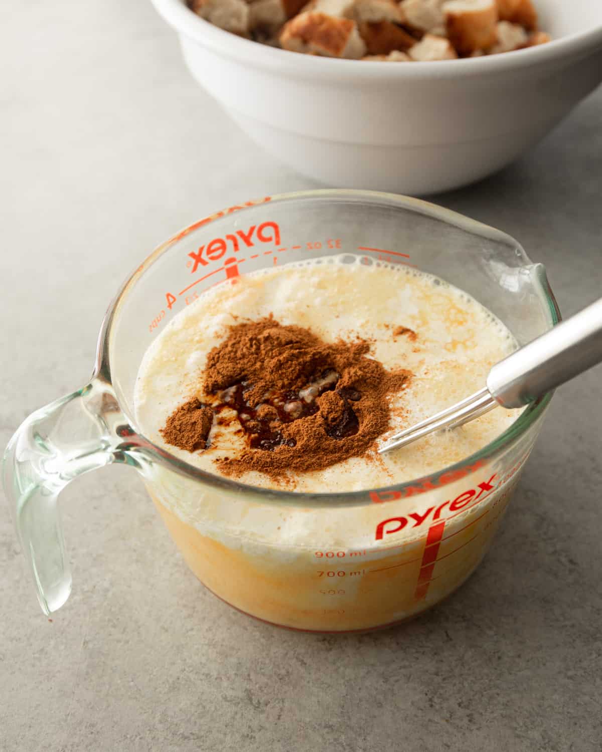 mixing cinnamon into egg mixture in a glass measuring cup