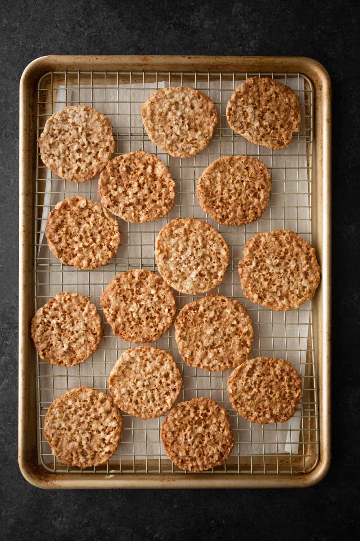 oatmeal lace cookies on a parchment lined sheet pan